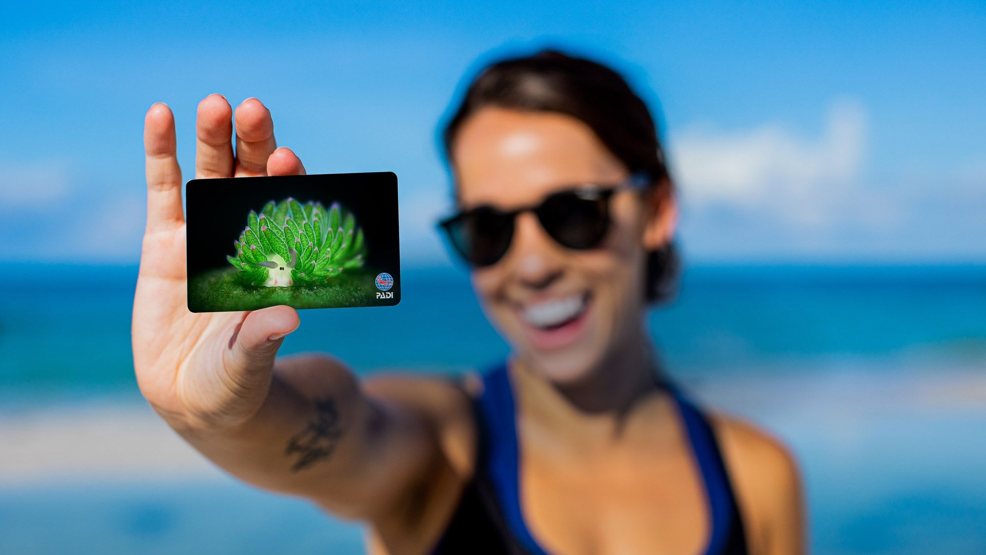 woman holding a PADI certification card to the camera