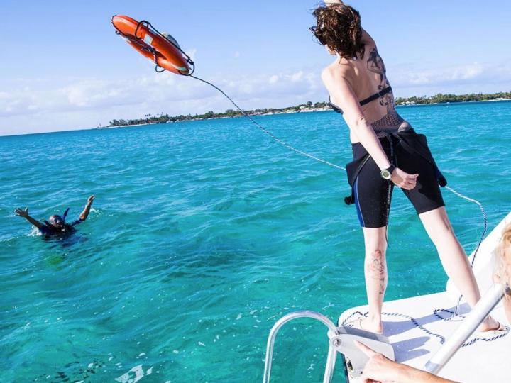 Throwing life preserver to diver near boat.